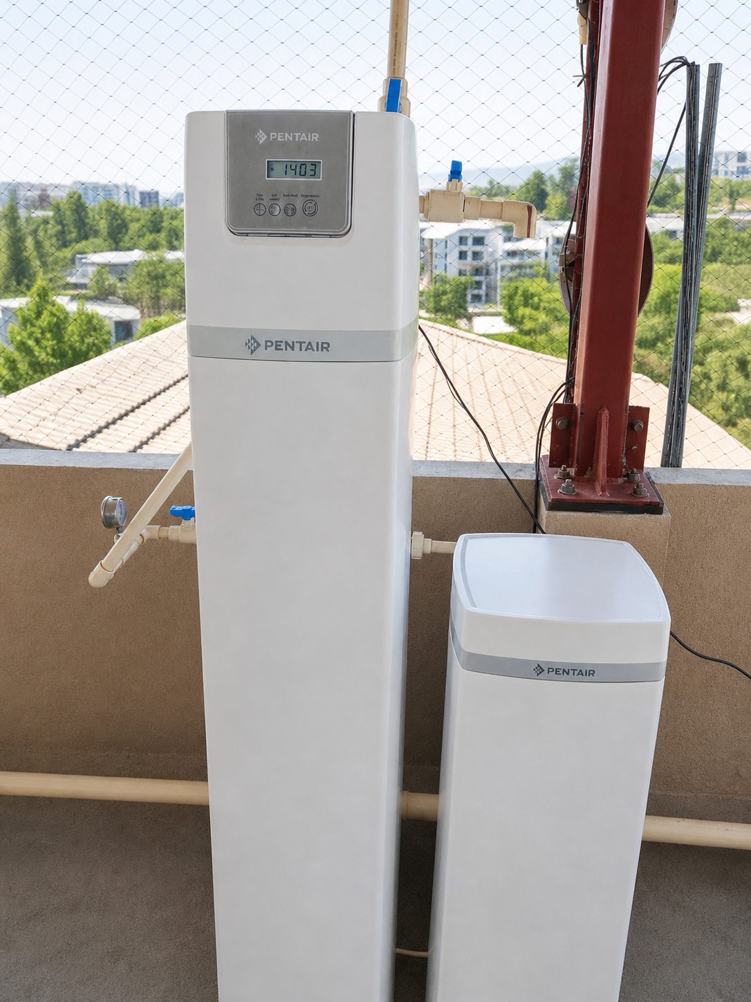 A commercial water softener column with its brine tank, installed by DhwaNeer on a service terrace